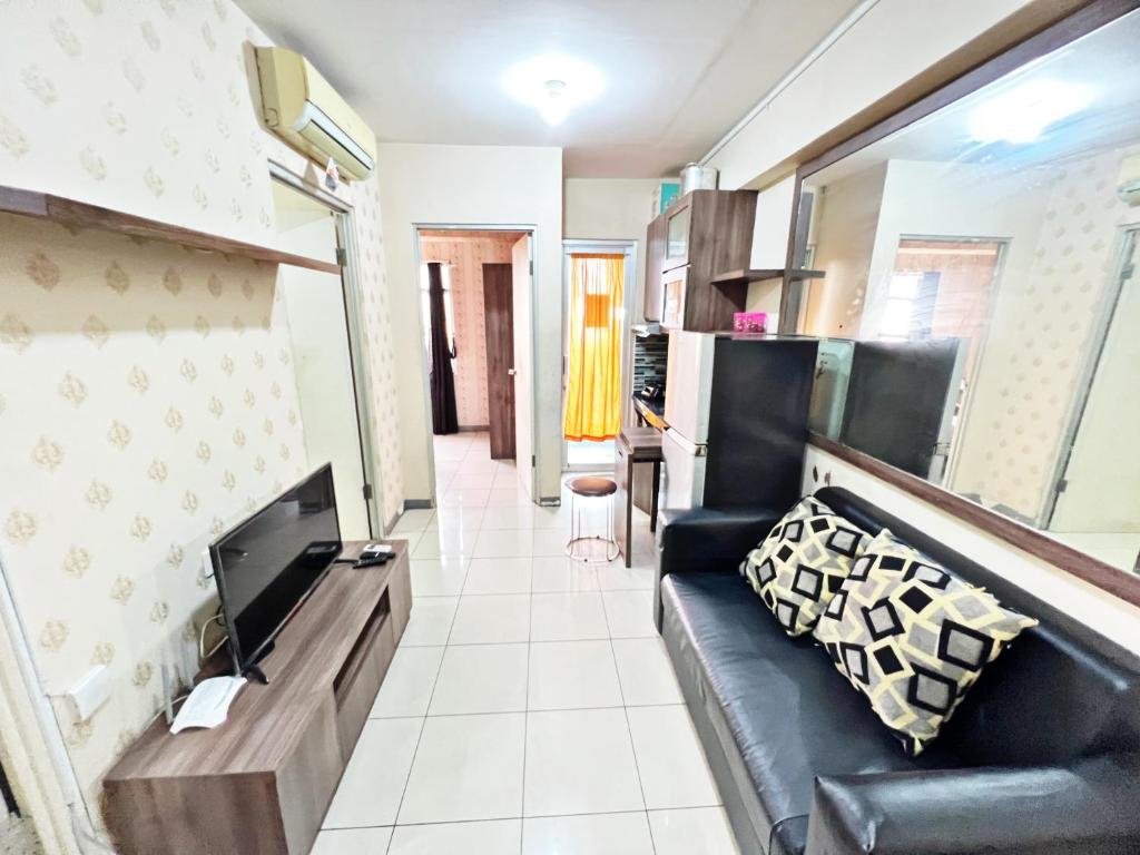 a living room with a couch and a television at Homie 2BR at Green Bay Pluit Apartment in Jakarta