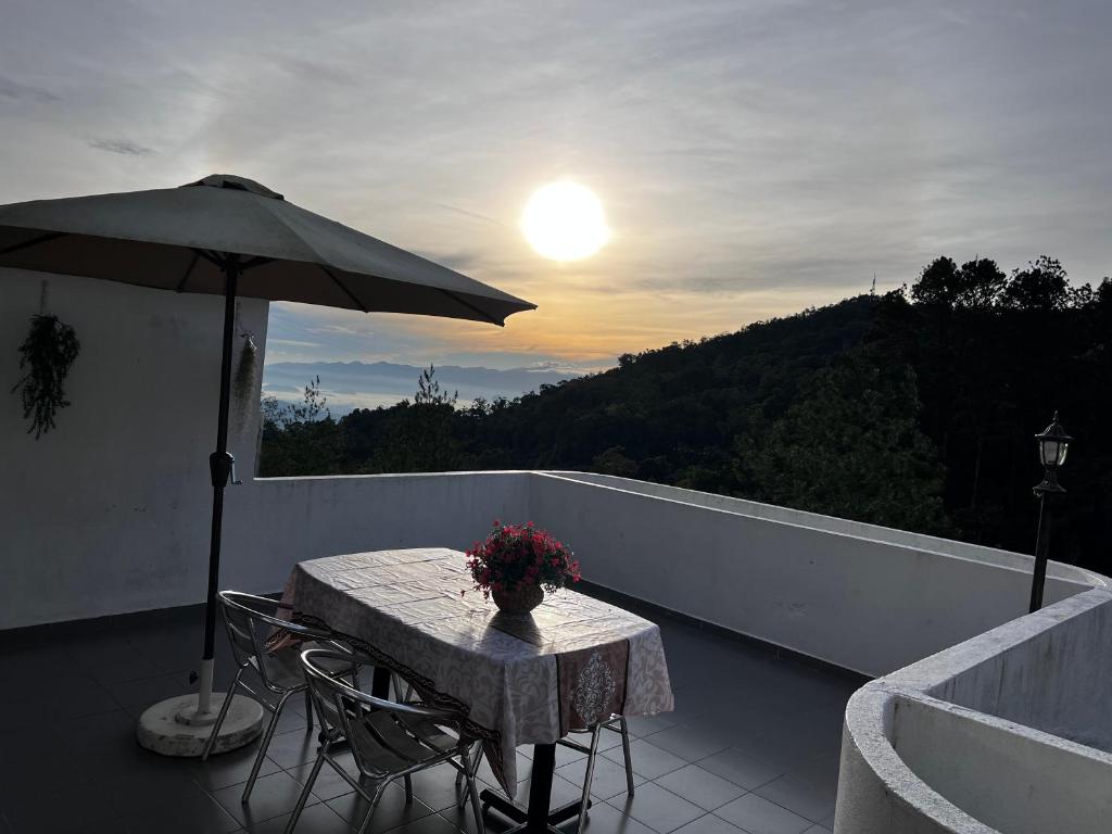 einen Tisch und Stühle auf einem Balkon mit Sonnenschirm in der Unterkunft THE MILKY WAY @ PINE RESORT in Bukit Fraser