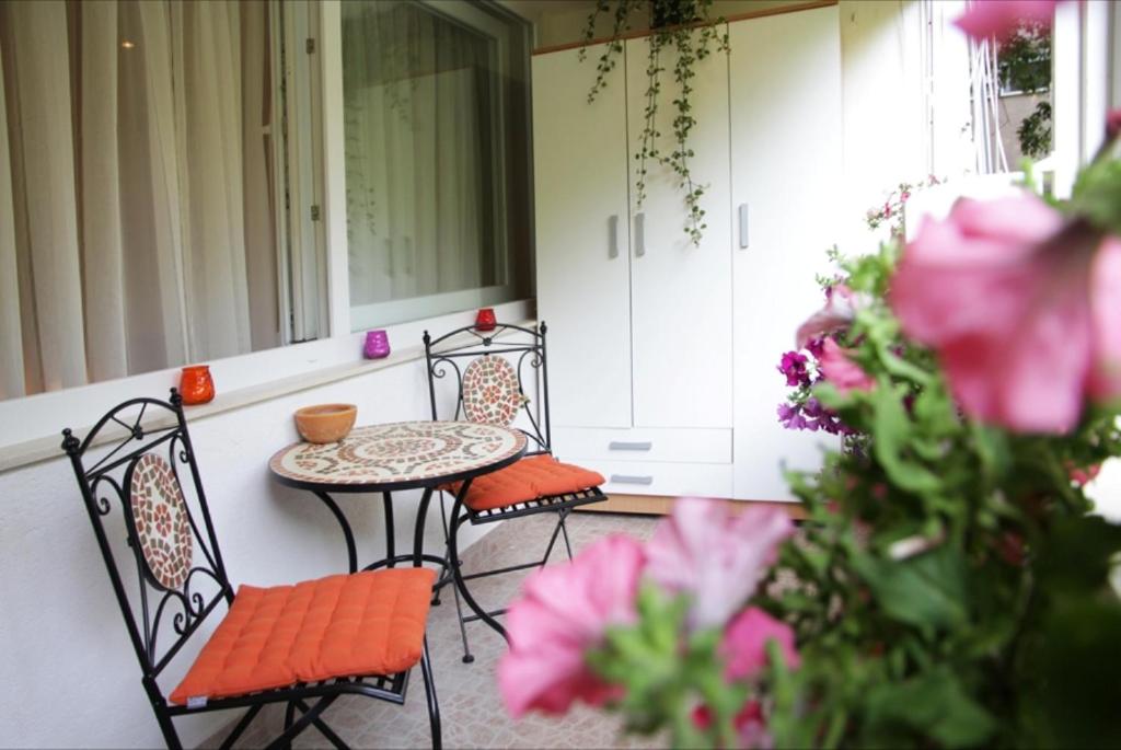 un porche con mesa, sillas y flores rosas en Apartment Tea 2, en Split