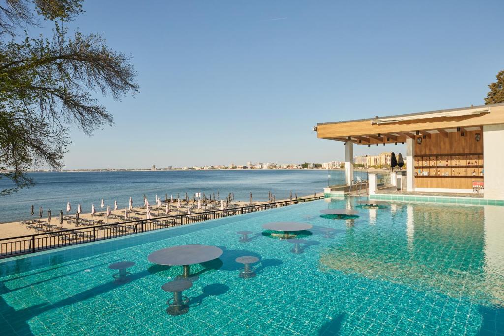 een zwembad met tafels en stoelen naast het water bij Secrets Sunny Beach Resort and Spa - Premium All Inclusive - Adults Only in Sunny Beach