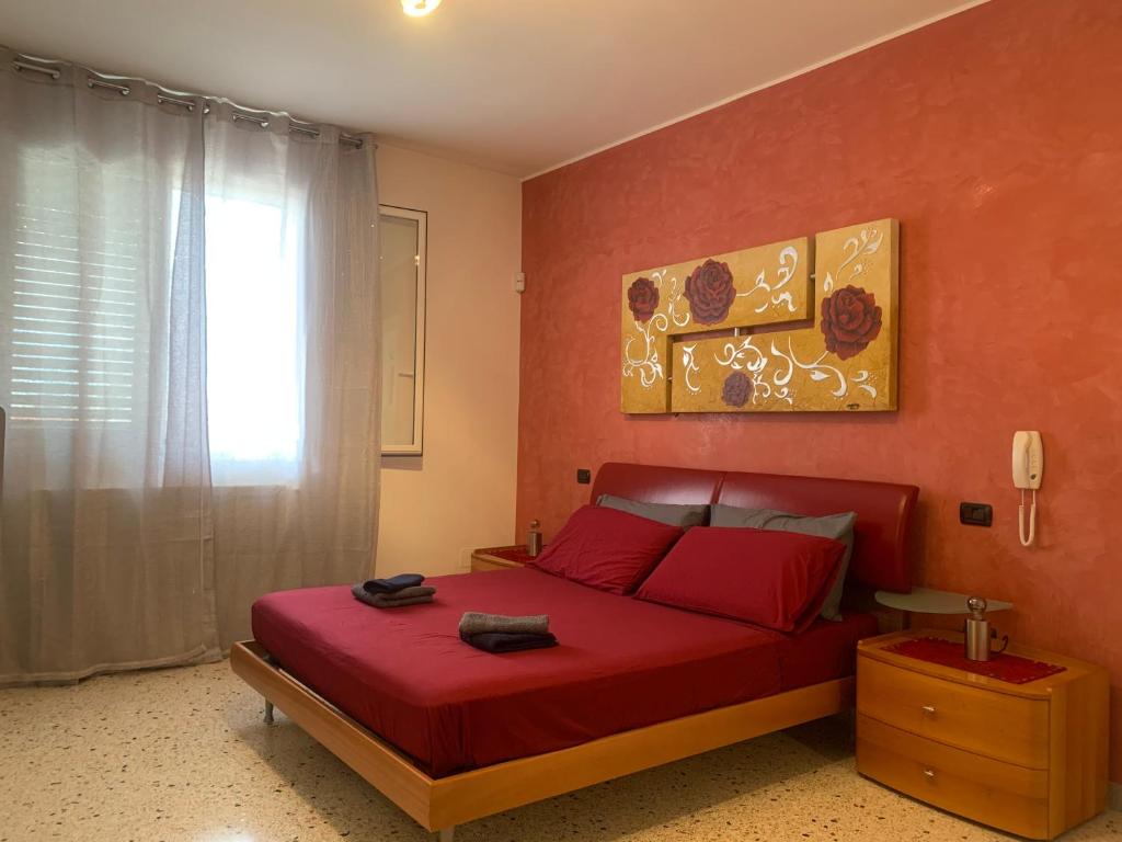 1 dormitorio con cama roja y ventana en Casa vacanza Ilaria, en Torre Lapillo