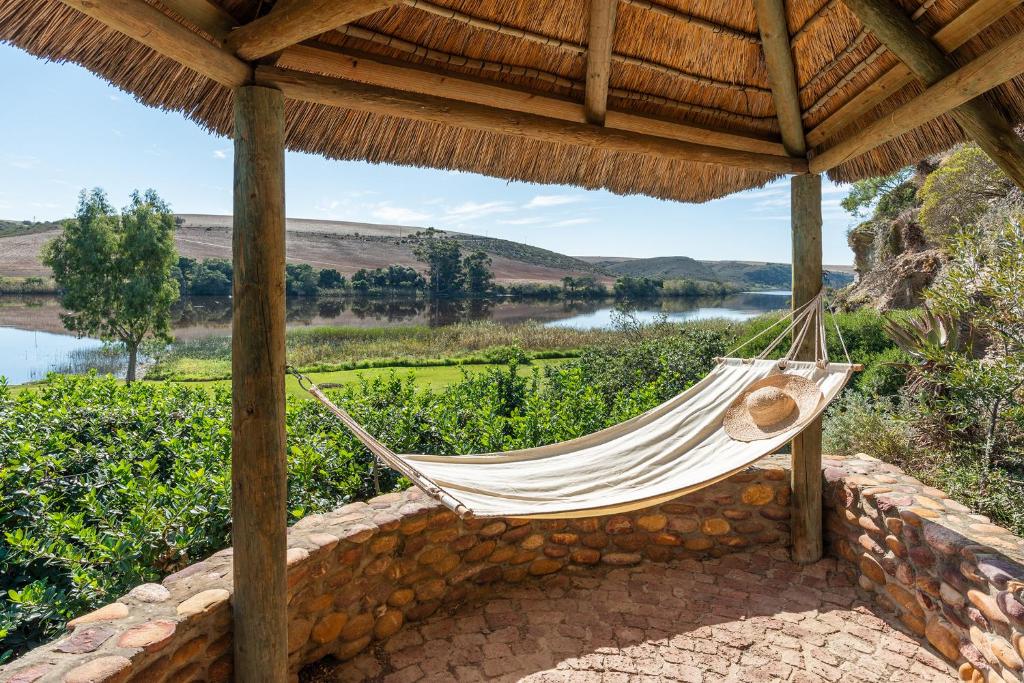 a hammock on a patio under a thatched roof at Tides River Lodge in Malgas