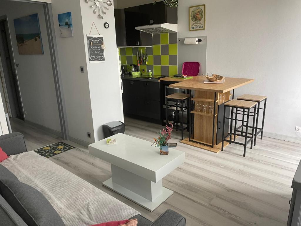 un salon avec une table et une cuisine dans l'établissement Le Pavillon - Appartement à 30 m de la plage, à Courseulles-sur-Mer