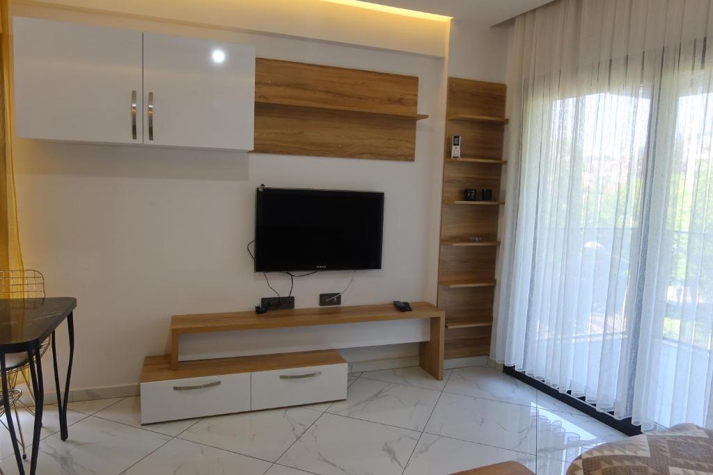 een woonkamer met een flatscreen-tv aan de muur bij MAYA APARTMANI in Kuşadası