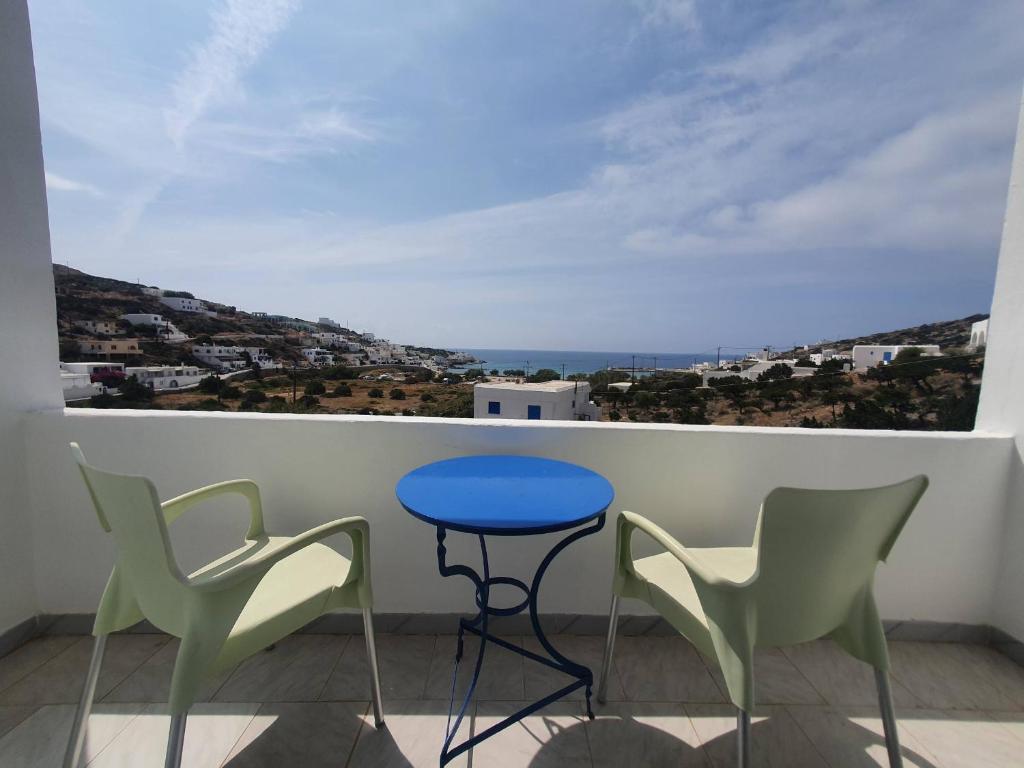 a balcony with a blue table and two chairs at Galini Rooms Sikinos Travel in Síkinos