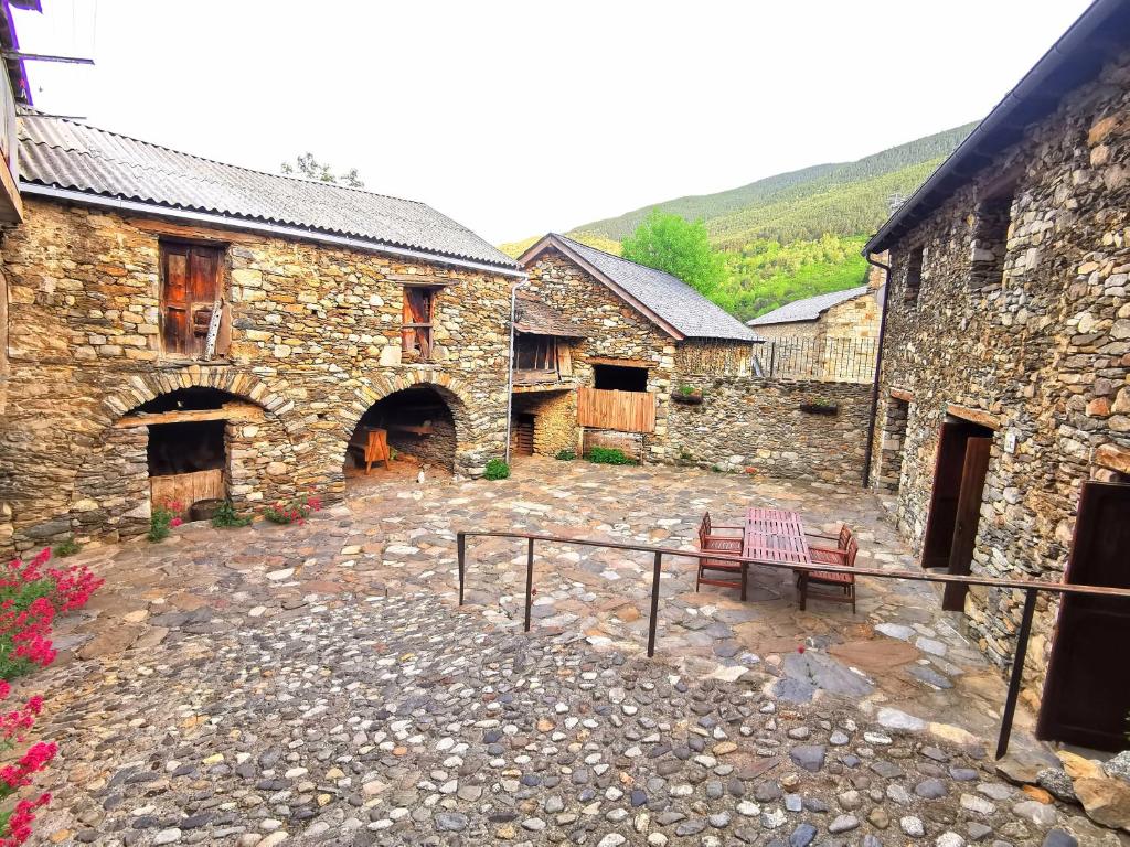 a stone building with a bench in a courtyard at Tríplex con patio y BBQ en La Vall de Boí in Cardet