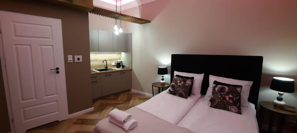 a bedroom with a bed with two pillows and a bathroom at Apartament Salsa in Krakow