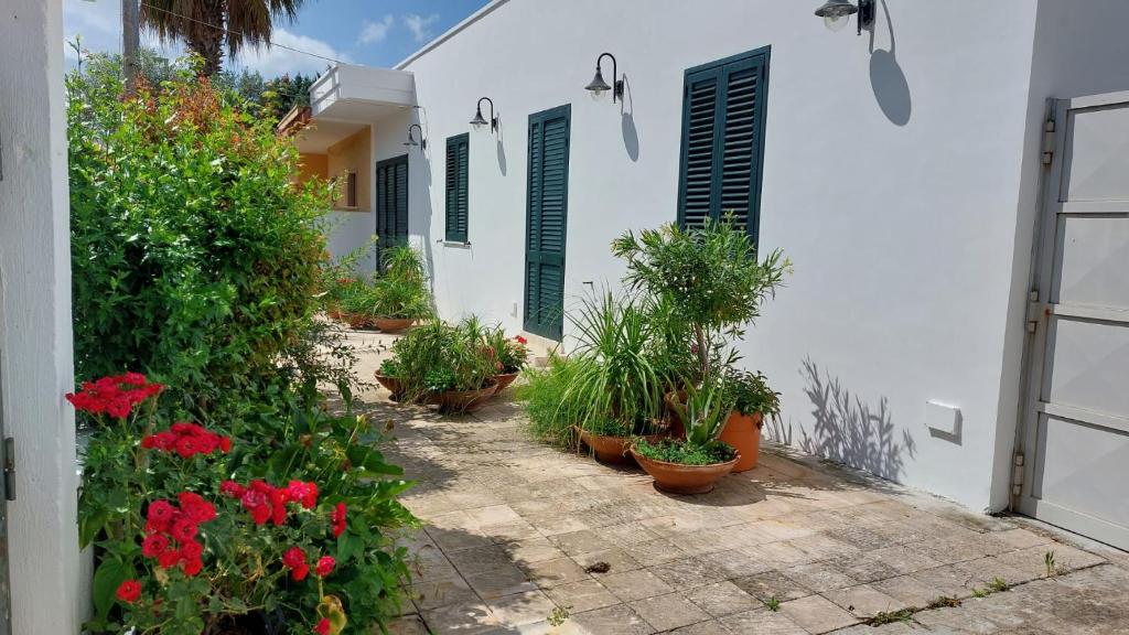 ein weißes Haus mit Pflanzen und roten Blumen in der Unterkunft Appartamento da Anna in Porto Cesareo
