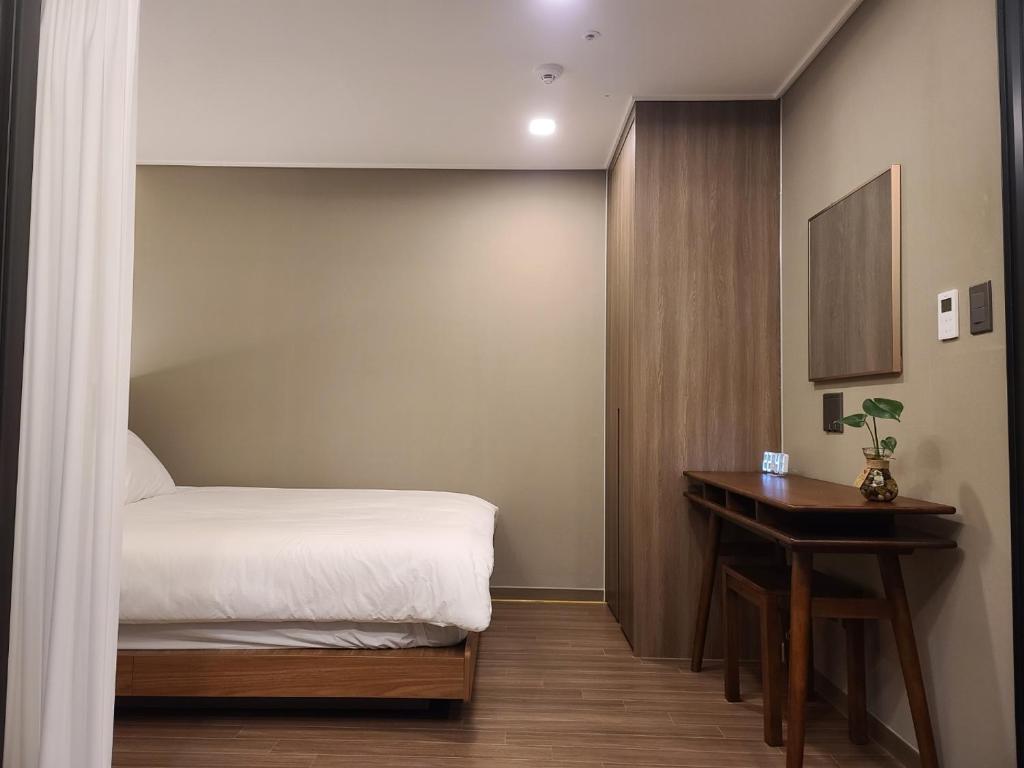 um pequeno quarto com uma cama e uma mesa em Elbon The Stay em Busan
