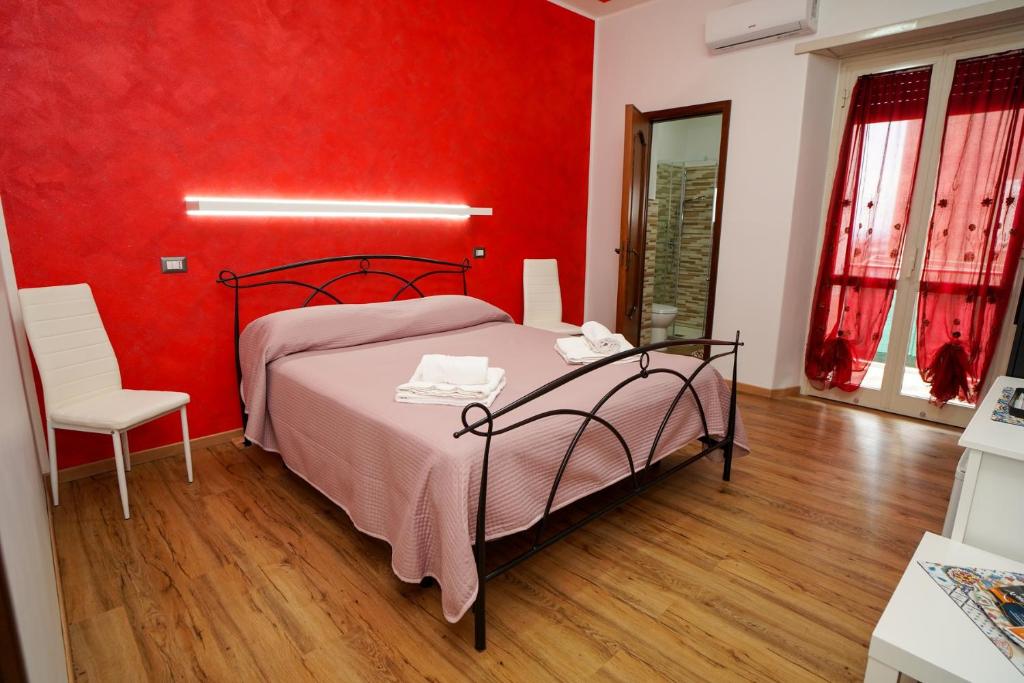 - une chambre rouge avec un lit et une chaise dans l'établissement Casa Mercy, à Catane