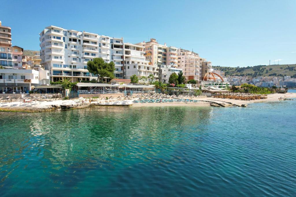 una playa con sillas y edificios en el agua en Oceanic Overview Suites, en Sarandë