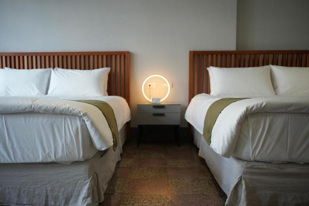 duas camas num quarto com um candeeiro numa mesa de cabeceira em 璿 旅 Syuan Hotel em Tainan