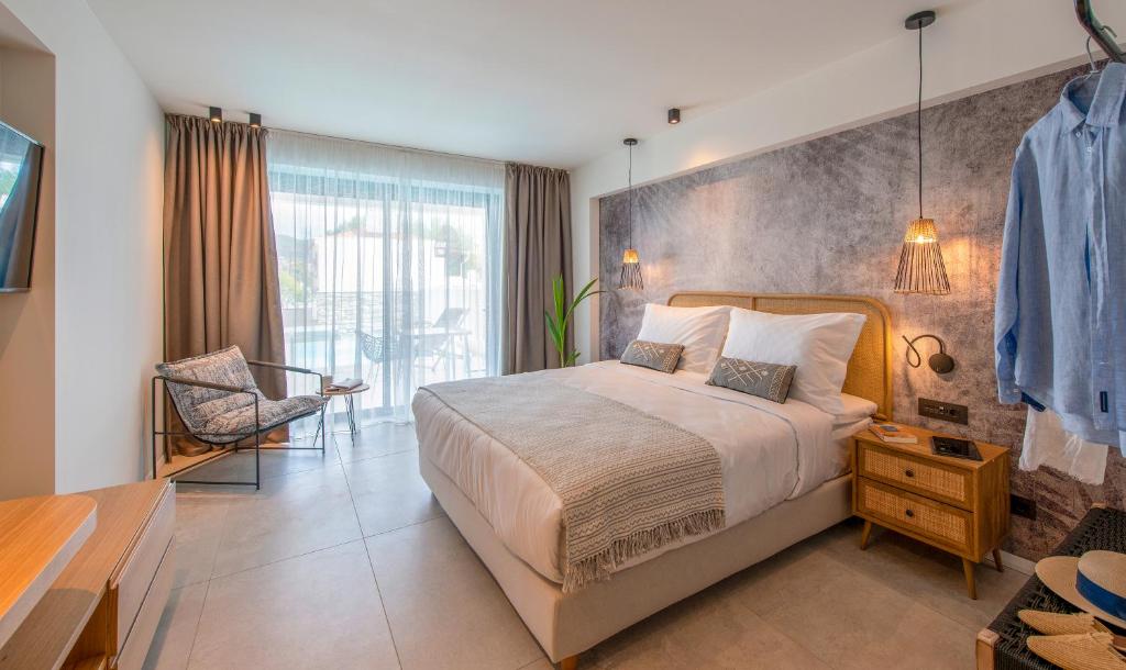 a bedroom with a large bed and a chair at Alea Suites -Adults Only and Kids 14 Plus in Asprovalta