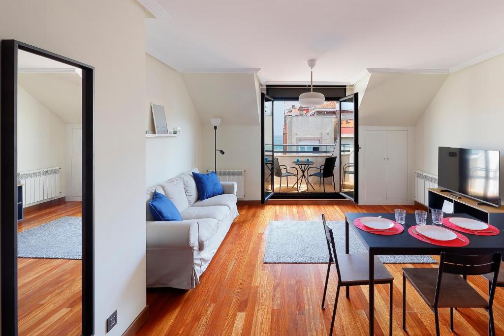 een woonkamer met een bank en een tafel bij Ático con terraza, vistas al mar y parking en playa de S Lorenzo in Gijón