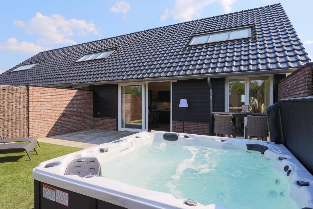 una bañera de hidromasaje en el patio trasero de una casa en Erve Mulder vakantiehuis met eigen jacuzzi en eigen sauna en Weerselo