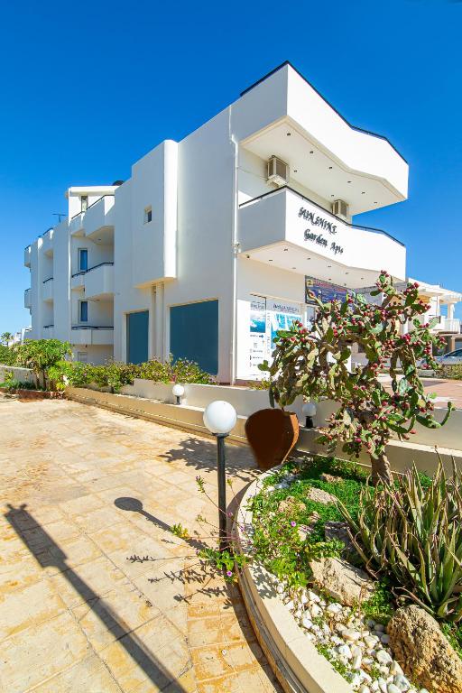 a building with a tree in front of it at Sunshine Garden Apts in Malia