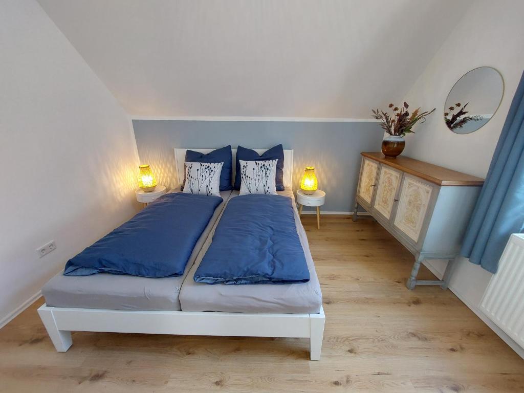 a bedroom with a bed with blue sheets and two lamps at Gemütliche Familienwohnung in der Nähe des Nordparks und des Norparkcenters! in Bielefeld