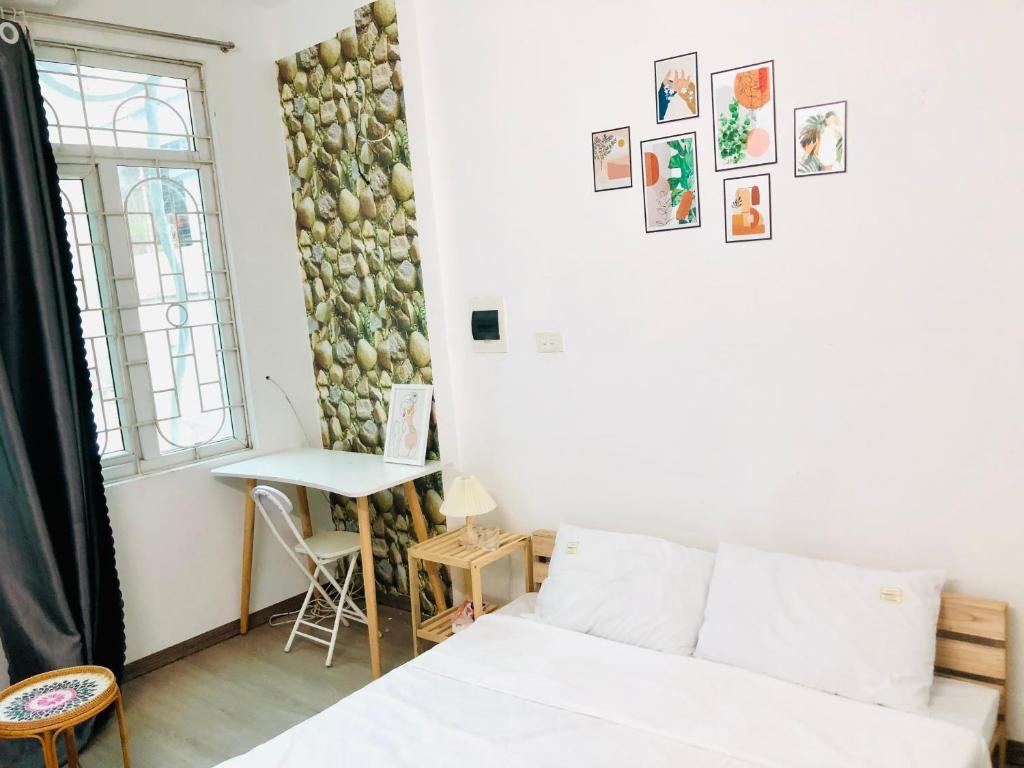 a living room with a white bed and a table at Mika Homestay Simple & Cozy in Hanoi