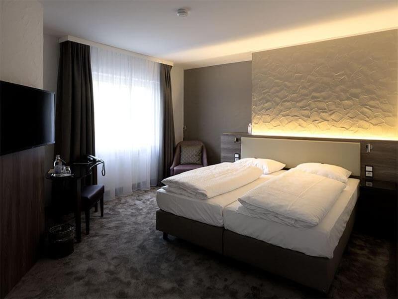 ein Hotelzimmer mit einem Bett und einem TV in der Unterkunft Hotel Am Park in Leinfelden-Echterdingen