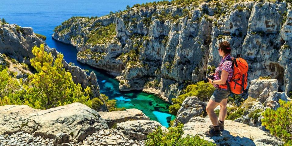a man with a backpack standing on top of a mountain at Cabanon du Pêcheur, Parc National des Calanques in Marseille