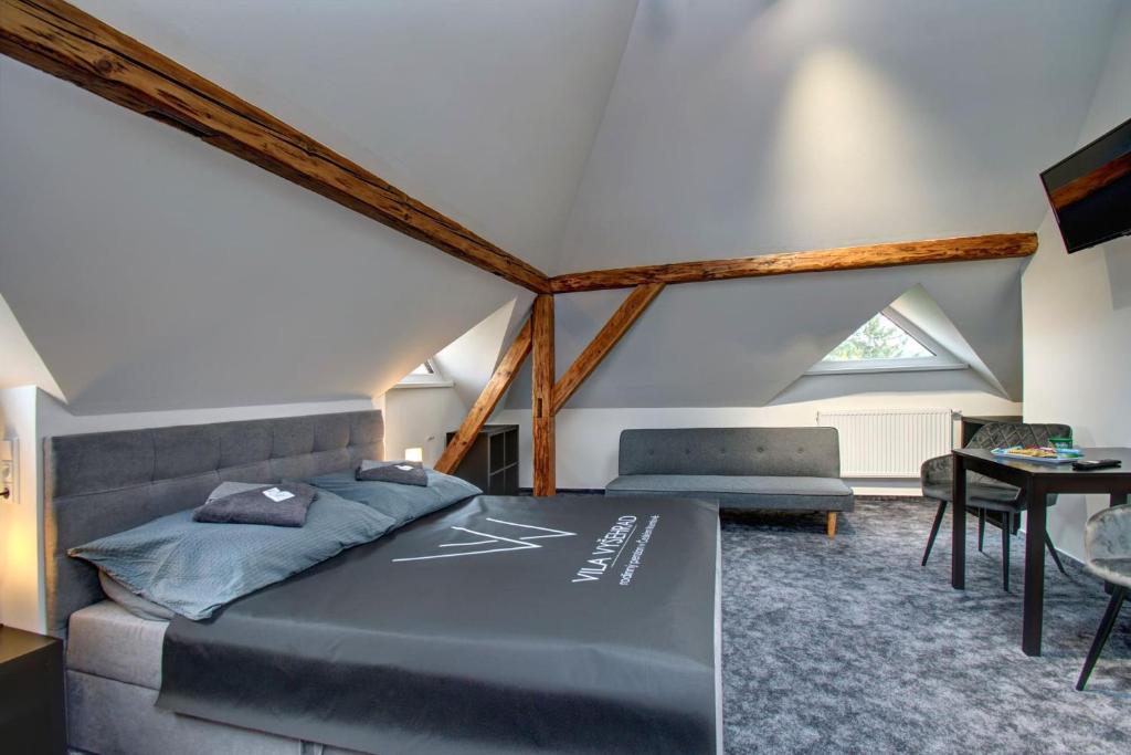 a attic bedroom with a bed and a table at Vila Vyšehrad in Český Krumlov