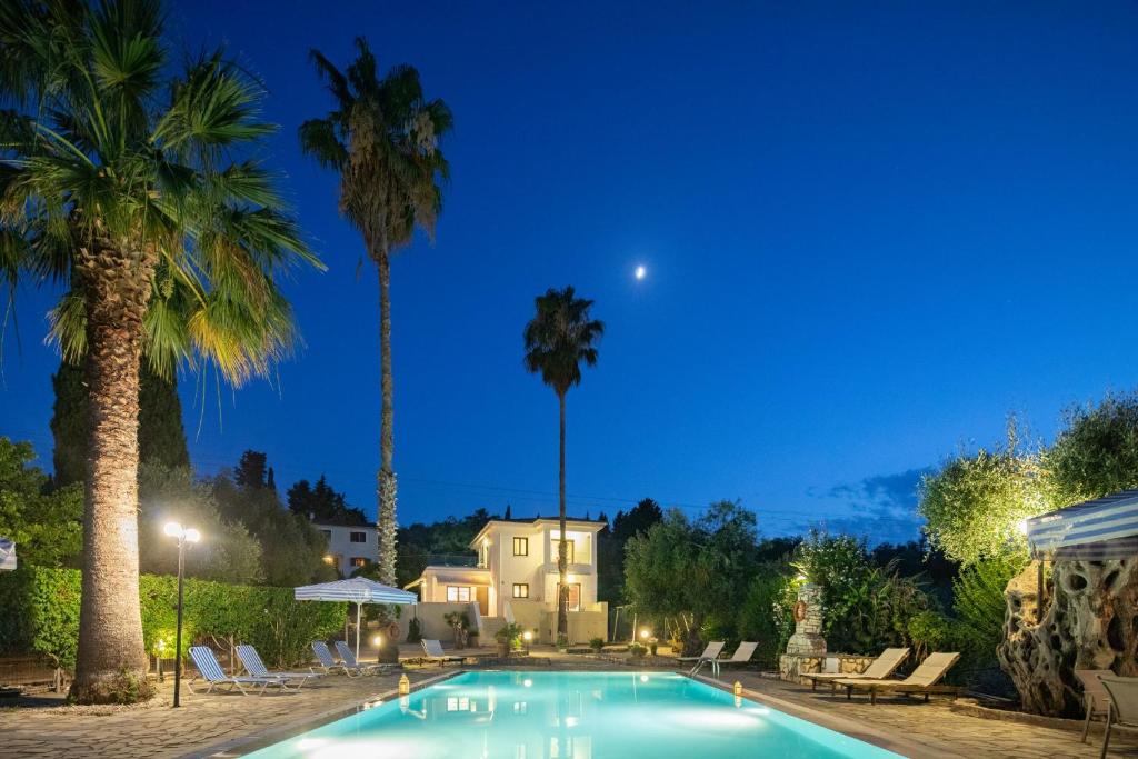 a pool with palm trees and a house at night at Villa Lianolia in Perítheia