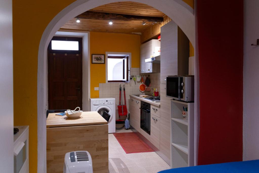 a kitchen with an archway leading to a kitchen with yellow walls at Miky's Flat in Marciana