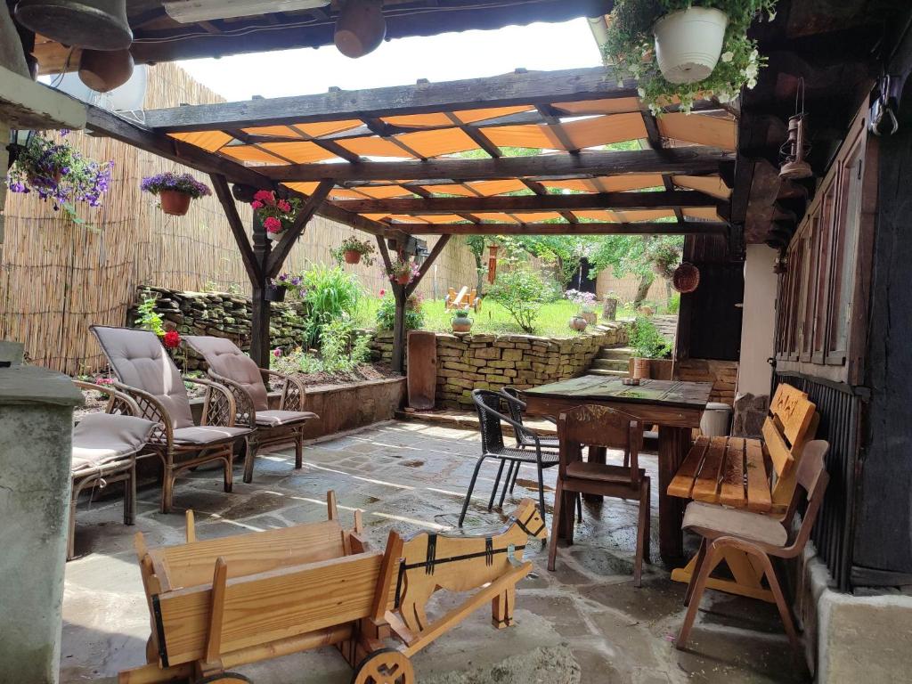 un patio con sillas, mesas y una pérgola de madera en Балтовата къща, en Medven