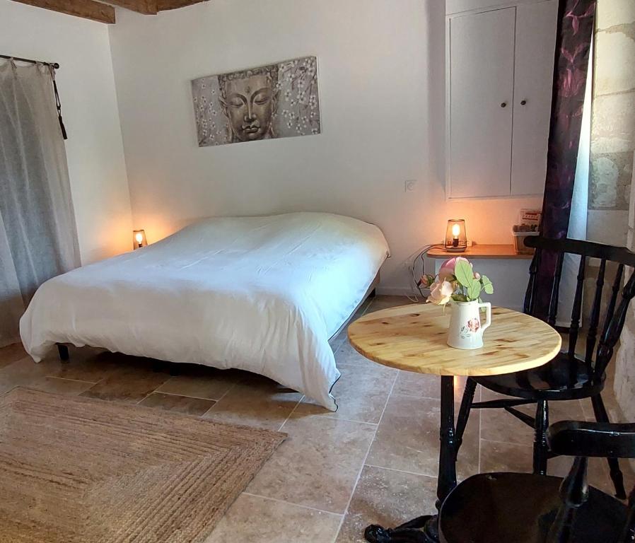 a bedroom with a bed and a wooden table at Le Clos des Roses in Parçay-les-Pins