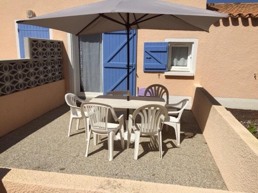 - une table et des chaises sous un parasol sur la terrasse dans l'établissement Villa 4 pers climatisée, piscine, près commerces et plage, courts de tennis à proximité - FR-1-81-219, au Barcarès