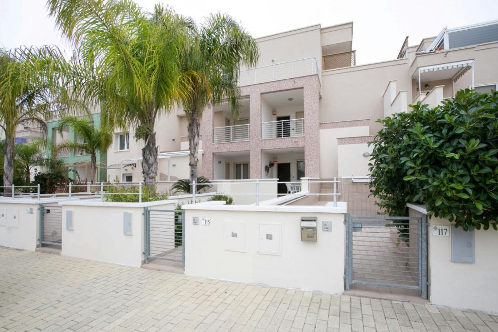 a building with white walls and palm trees at La Perla in Gallipoli