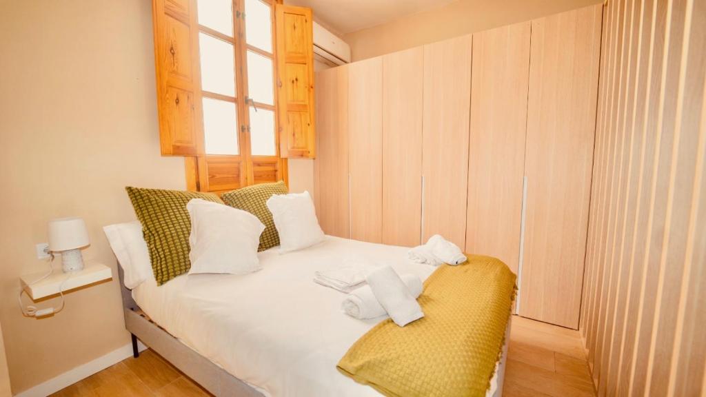 Un pequeño dormitorio con una cama con toallas. en El ALMA de Granada, en Granada