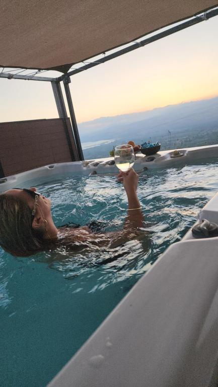 a woman in a bath tub with a glass of wine at הרימון- צימר בוטיק לזוג במעלה גמלא in Ma'ale Gamla