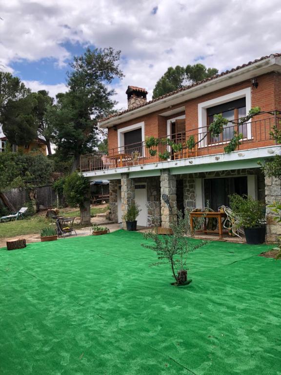 una casa con un césped verde delante de ella en Casa Rural Pantano de San Juan, en Pelayos de la Presa