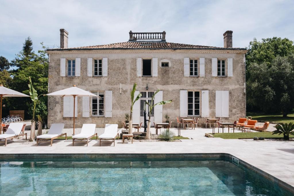 une maison avec une piscine en face d'une maison dans l'établissement Le Château Réal, à Saint-Seurin-de-Cadourne