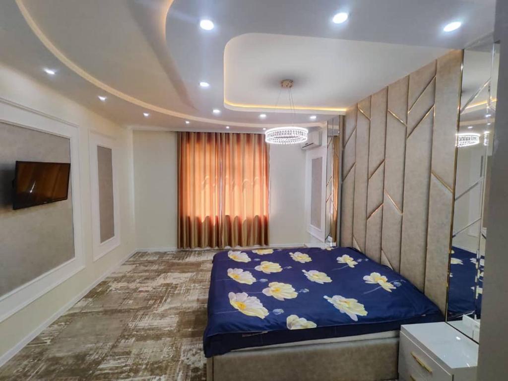 a bedroom with a blue bed with flowers on it at Golden Apartments in Khujand