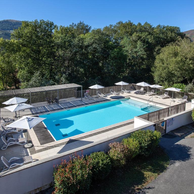 une piscine avec chaises et parasols sur un immeuble dans l'établissement VVF Pays Basque Saint-Étienne-de-Baïgorry, à Saint-Étienne-de-Baïgorry