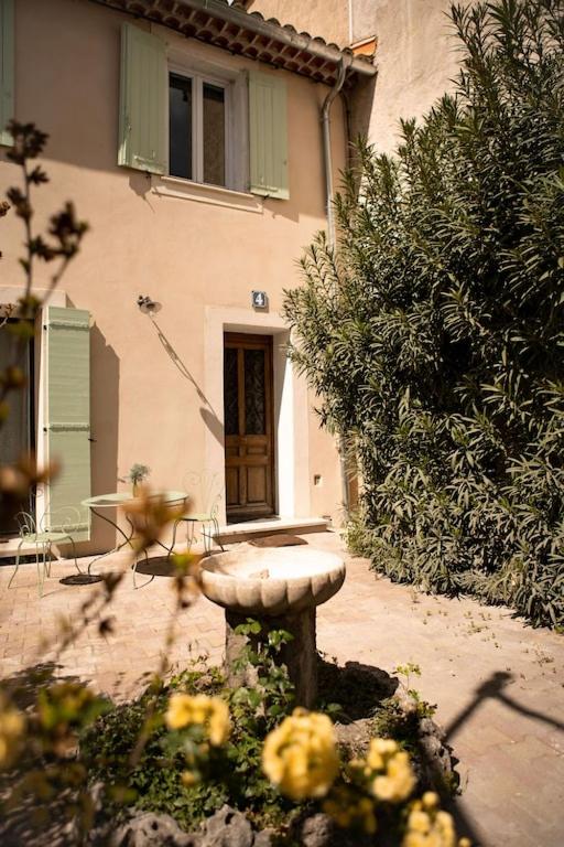 un jardin avec une fontaine en pierre en face d'une maison dans l'établissement La maison du bassin, à LʼIsle-sur-la-Sorgue