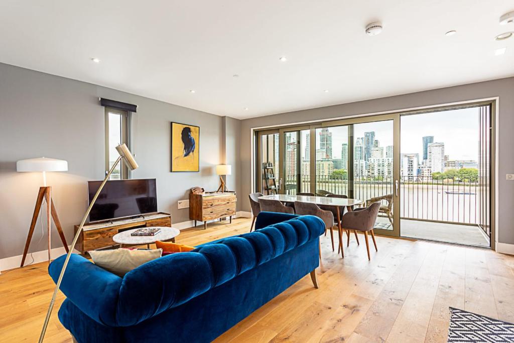 a living room with a blue couch and a large window at Stunning Surrey Quays Flat in London