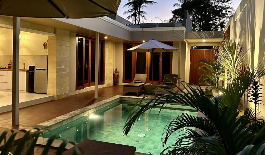 a swimming pool in a house with an umbrella at Pandan Villas in Selong Belanak