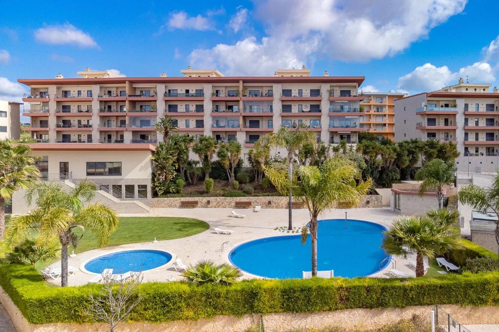 - Vistas a un hotel con 2 piscinas y palmeras en Cozy modern apartment 111 by Destination Algarve, en Lagos