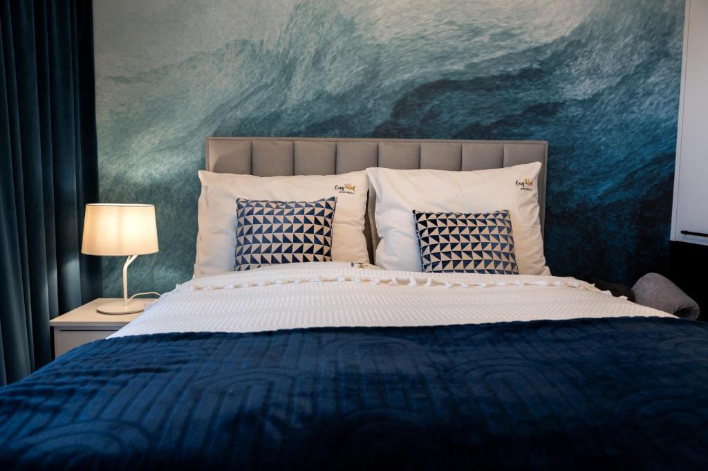 Un dormitorio con una cama azul con almohadas y una pintura en Nadmorski Loft Rezydencja Niechorze 116 plaża ogród, en Niechorze
