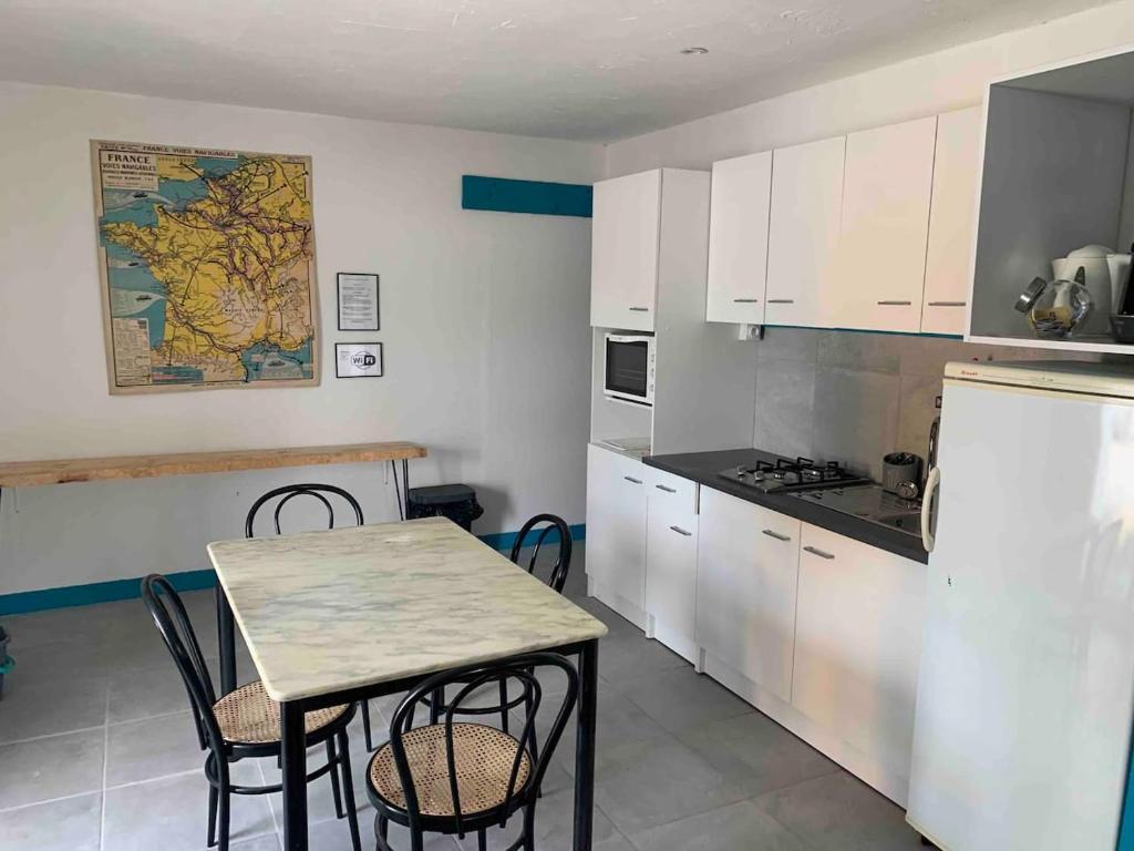 a kitchen with white cabinets and a table and chairs at LE DEPOT appartement du port à Champvert in Champvert