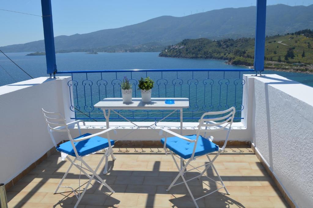 einen Tisch und Stühle auf einem Balkon mit Blick auf das Wasser in der Unterkunft Rania Bella Vista Studios in Poros
