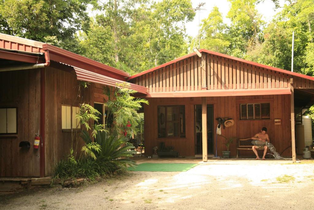 una mujer sentada en un banco frente a una casa en Tropical Bliss bed and breakfast en Mena Creek