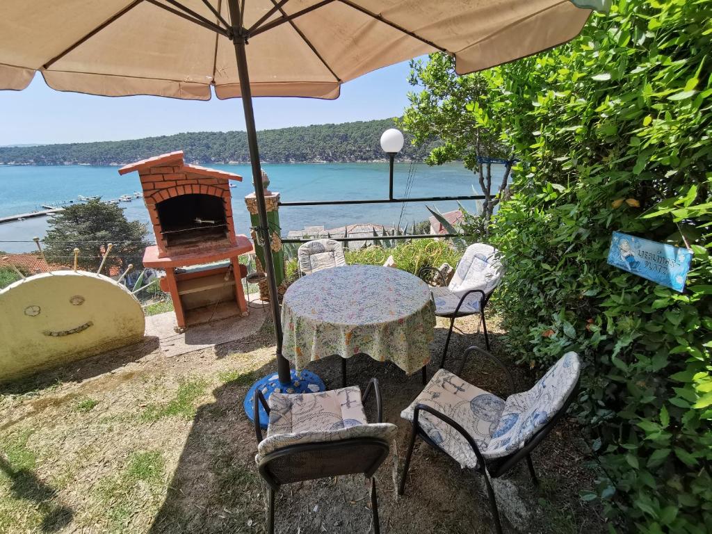 une table et des chaises avec un parasol et un grill dans l'établissement Cosy room Arba with private bathroom and sea view, à Kampor