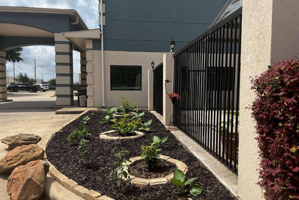 a garden in front of a building with a fence at Super 8 by Wyndham Pasadena in Pasadena