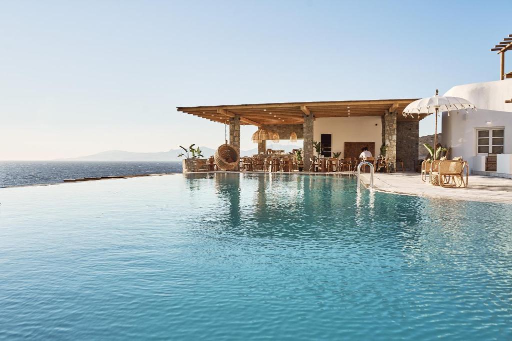 a large swimming pool next to the ocean at Ubud Mykonos in Agios Ioannis Mykonos
