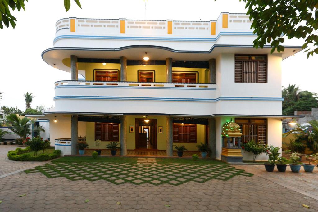 um grande edifício branco com um pátio em frente em Les Boganveillea Heritage Guest House em Auroville