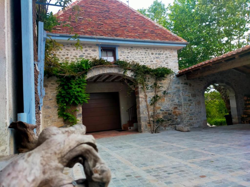 a brick house with a garage and an archway at Entre Galets in Sauveterre